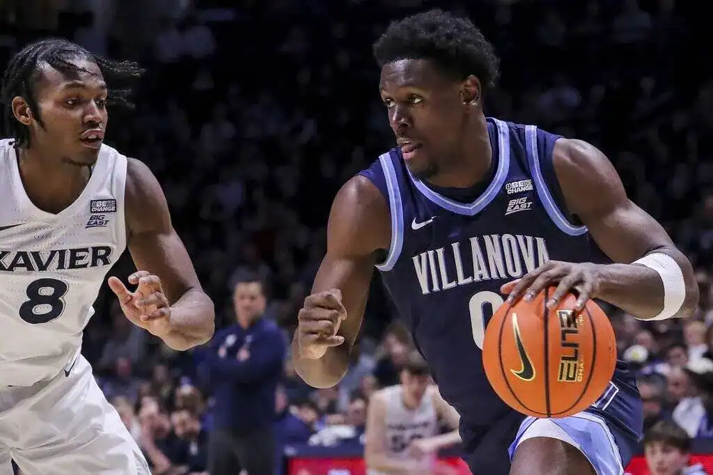 Villanova player driving with the basketball while being closely guarded by a Xavier defender in NCAA play.