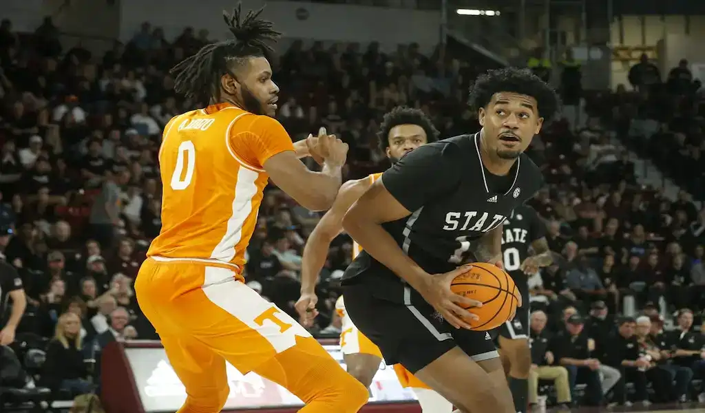 Mississippi State Bulldogs player drives to the basket while being defended by a Tennessee Volunteers player during a college basketball game.