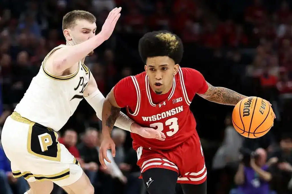 Wisconsin Badgers guard dribbles past a Purdue defender, showing speed and control during an NCAA college basketball game