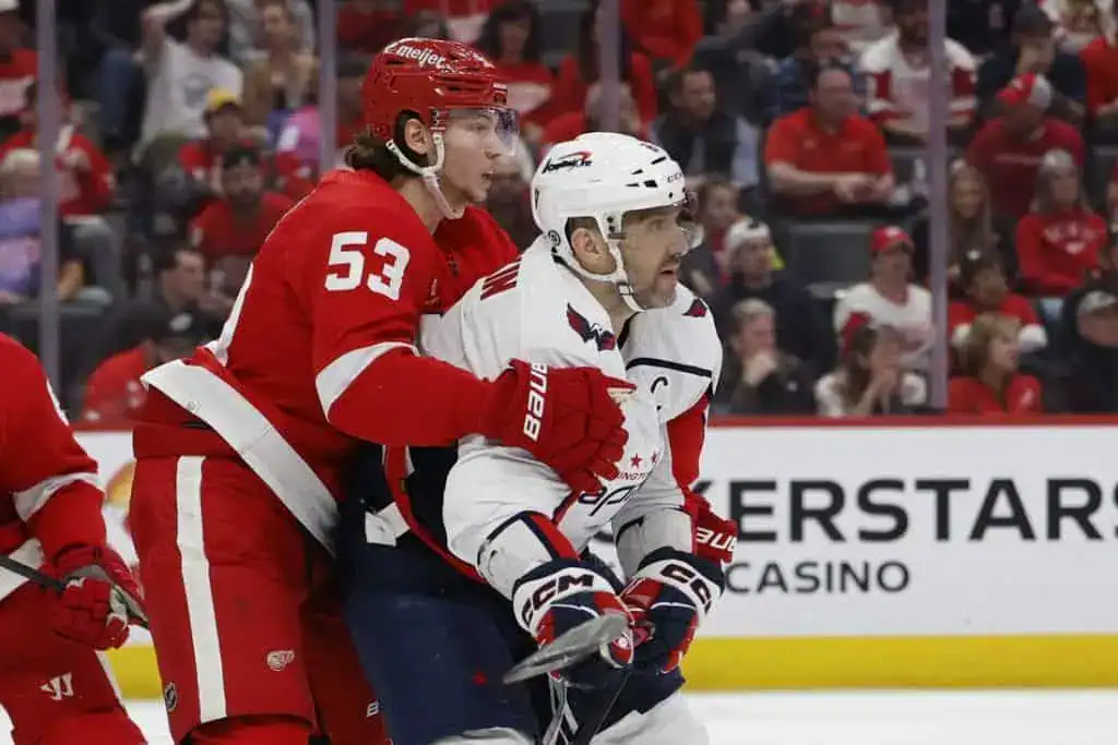 Detroit Red Wings player locking up defensively with a Washington Capitals player during an NHL game.