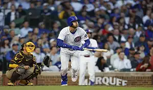 Chicago Cubs batter follows through on a hit against the San Diego Padres as catcher readies for play