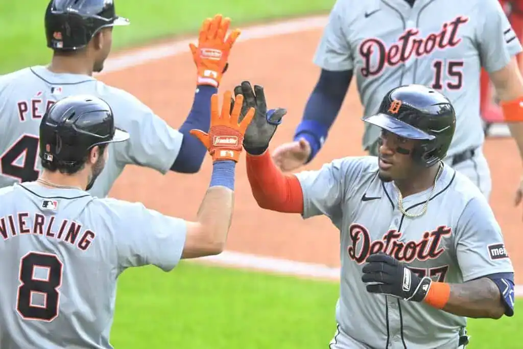 7 Detroit Tigers players in gray uniforms celebrate a score with high-fives.