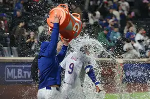 MLB player gets doused with a cooler of water in celebration after a game.