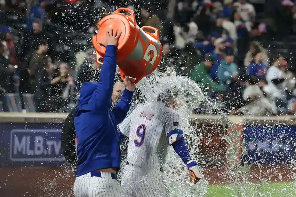 MLB player gets doused with a cooler of water in celebration after a game.