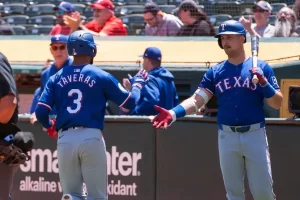 Texas Rangers baseball players exchange a fist bump near the dugout.