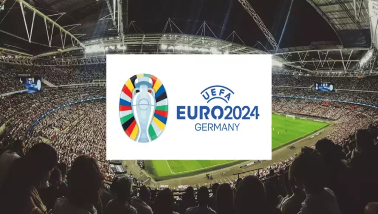 Crowd-filled stadium during a UEFA Euro 2024 match, featuring the tournament logo centered in front of the field.