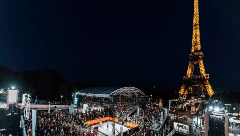 A lively night scene in Paris, featuring a crowded sports event near the illuminated Eiffel Tower amidst a vibrant atmosphere.