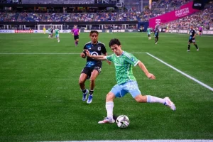 Seattle Sounders player prepares to cross the ball near the corner flag while being defended by a Minnesota United player.