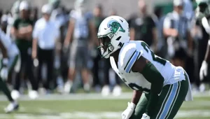 A football player in a green and white uniform stands ready on the field, focused and poised for action during a game.