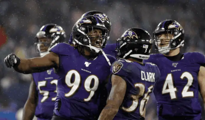 Houston Texans vs Baltimore Ravens Picks and Predictions December 25th 2024 2 Baltimore Ravens players in purple uniforms, including #99 and #36, celebrate a big play during an NFL game in rainy conditions.