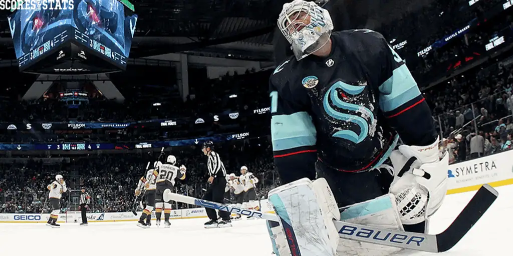 Seattle Kraken vs Arizona Coyotes Picks and Predictions December 30th 2024 2 A Seattle Kraken goalie in a dark uniform kneels on the ice, watching as the opposing team celebrates a goal in a packed arena.