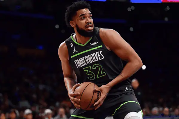 New York Knicks vs Toronto-raptors Picks and Predictions December 23rd 2024 2 Minnesota Timberwolves' Karl-Anthony Towns holding the basketball while scanning the court during a game, wearing the team's black and green uniform.