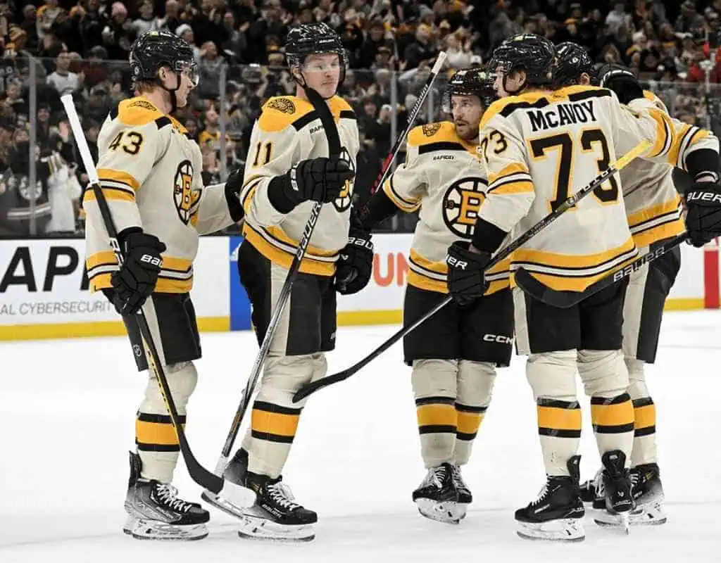 Buffalo Sabres vs Boston Bruins Picks and Predictions January 28th 2025 2 Five Boston Bruins players celebrate a goal on the ice, wearing their white and black jerseys, surrounded by an excited crowd.