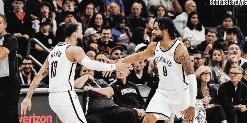 Brooklyn Nets vs Indiana Pacers Picks and Predictions January 6th 2025 3 Brooklyn Nets players Cameron Payne (#13) and D'Angelo Russell (#9) exchanging a high-five on the court with fans watching in the background.