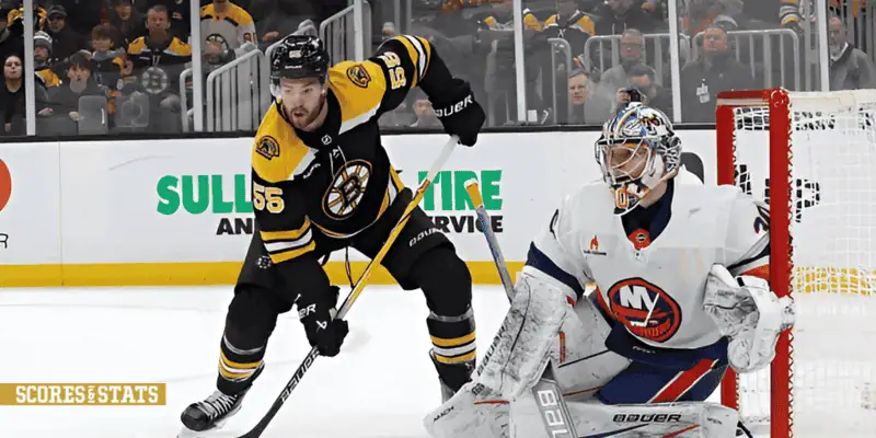 Boston Bruins vs Edmonton Oilers Picks and Predictions January 7th 2025 2 Boston Bruins player maneuvers the puck near New York Islanders goalie during intense NHL game action.