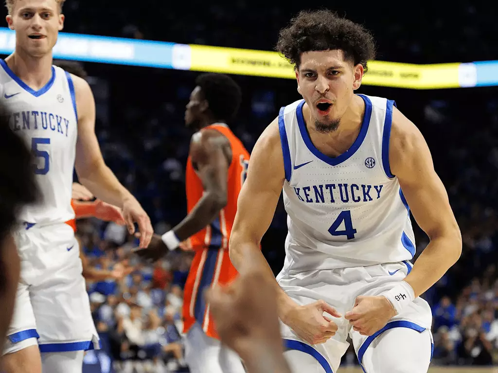 Kentucky Wildcats vs Texas A&m Aggies Picks and Predictions January 14th 2025 2 A Kentucky basketball player in a white uniform celebrates with intensity on the court, surrounded by teammates and opponents.