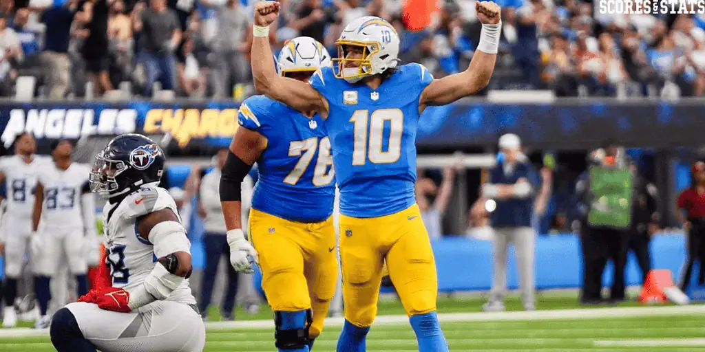 Las Vegas Raiders vs Los Angeles Chargers Picks and Predictions January 5th 2025 2 A football player in a blue jersey celebrates a successful play, raising his arms in triumph on the field with teammates nearby.