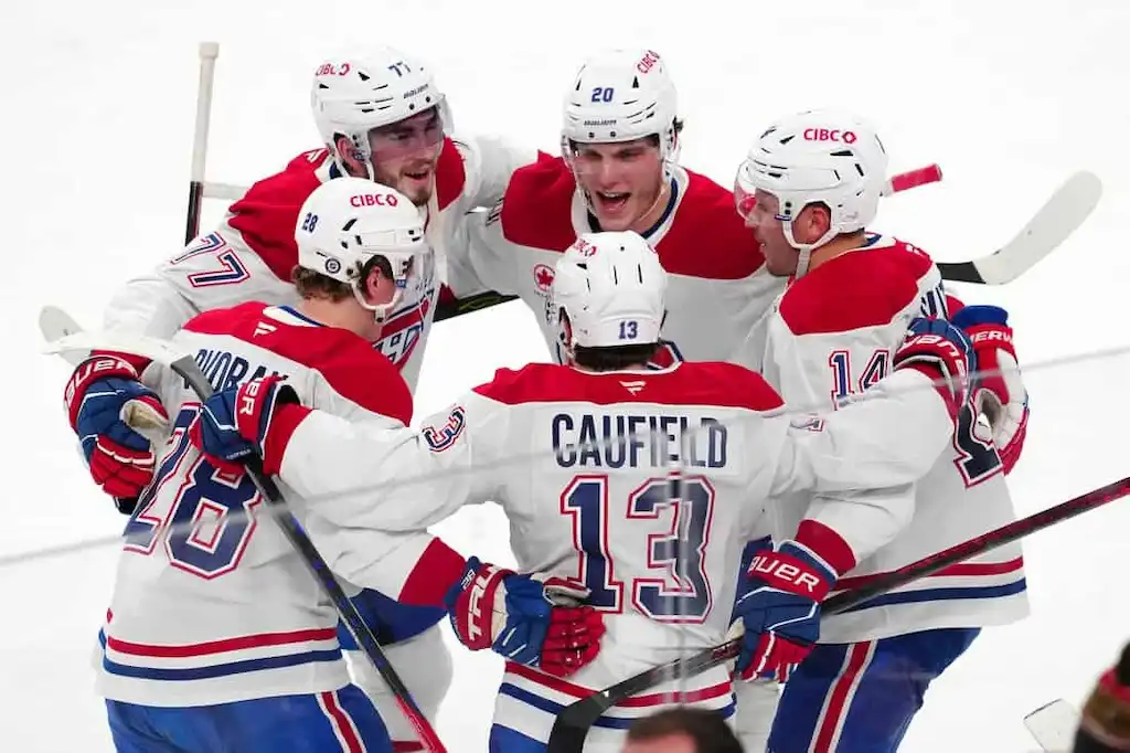 NHL 6 Montreal Canadiens players in white and red uniforms huddle together in celebration on the ice after a goal.