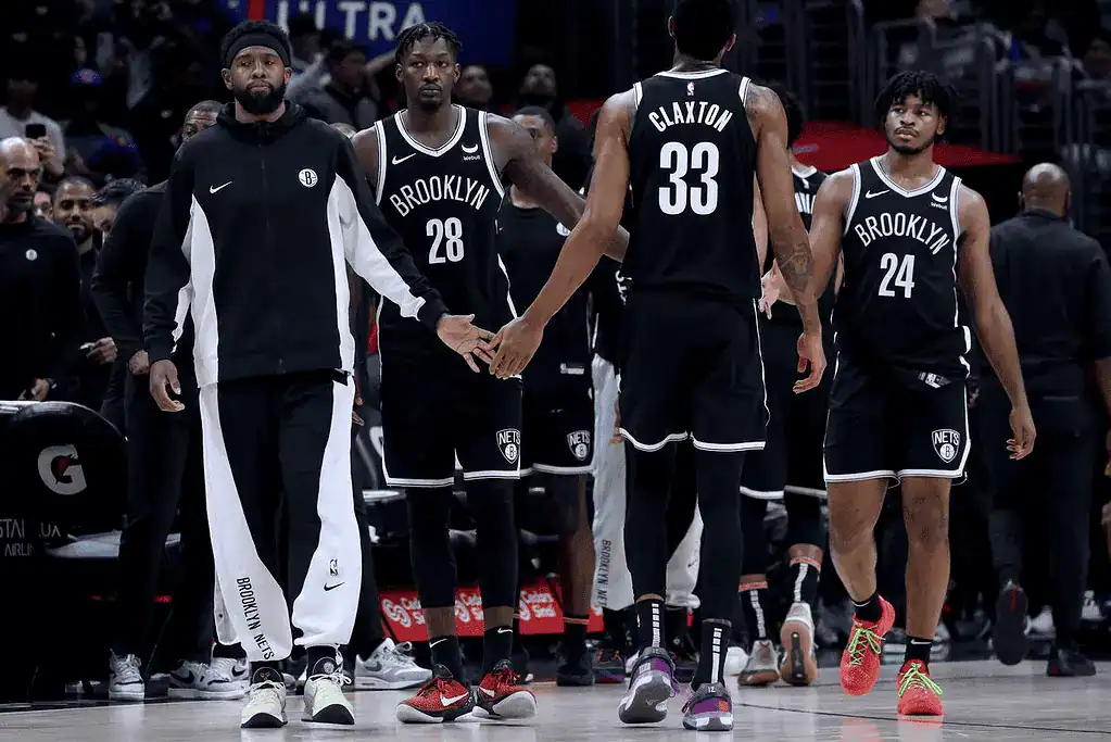 Charlotte Hornets vs Brooklyn Nets Picks and Predictions January 29th 2025 2 A group of Brooklyn Nets players in black uniforms share a moment on the court, showcasing team camaraderie during a game.