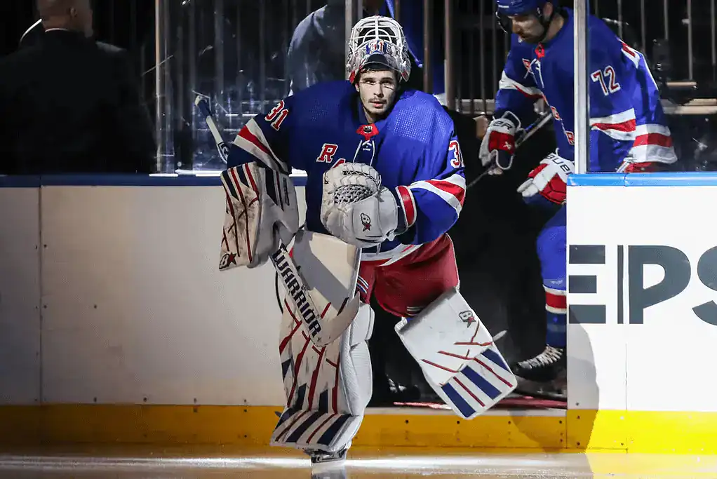New York Rangers vs Philadelphia Flyers Picks and Predictions January 23rd 2025 2 A hockey goalie in blue and red gear skates onto the ice, preparing for the game, while teammates follow closely behind.