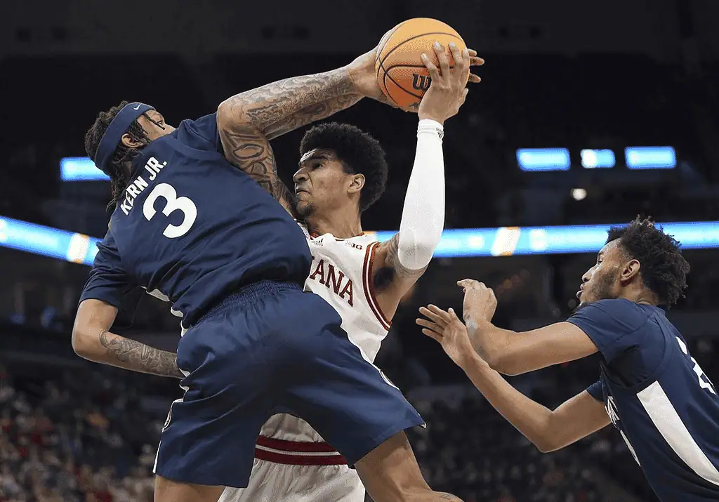 Penn State Lady Lions vs Rutgers Scarlet Knights Picks and Predictions January 20th 2025 2 A tense basketball moment where a player attempts a shot while being closely guarded by two opponents in a competitive game.