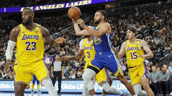 Golden State Warriors player Stephen Curry attempts a pass while being closely guarded by Los Angeles Lakers defenders, including LeBron James, during an NBA game.