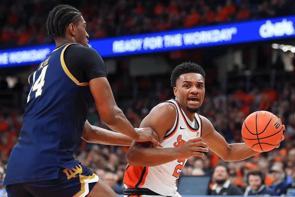 Syracuse Orange vs Pittsburgh Panthers Picks and Predictions January 25th 2025 2 A basketball player in an orange jersey dribbles the ball while being guarded by an opponent in a blue jersey during an intense game.