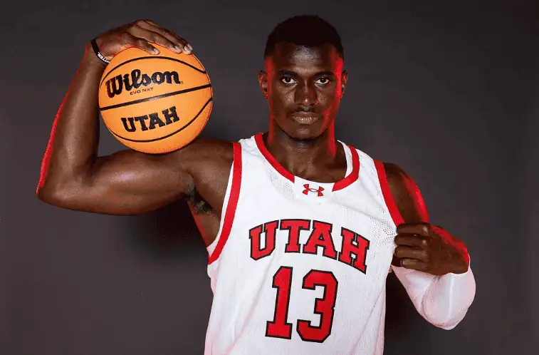 Utah Utes vs Cincinnati Bearcats Picks and Predictions January 28th 2025 2 A University of Utah basketball player wearing a white and red jersey with the number 13 poses confidently with a Wilson basketball resting on his shoulder.