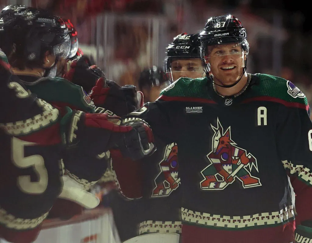Arizona Coyotes vs Winnipeg Jets Picks and Predictions January 20th 2025 2 Hockey players in unique green and maroon jerseys celebrate a goal with enthusiastic high-fives on the rink.