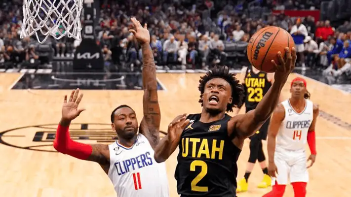 Golden State Warriors vs Utah Jazz Picks and Predictions January 28th 2025 4 Utah Jazz player drives to the basket for a layup while a Los Angeles Clippers defender attempts to block the shot during an NBA game.