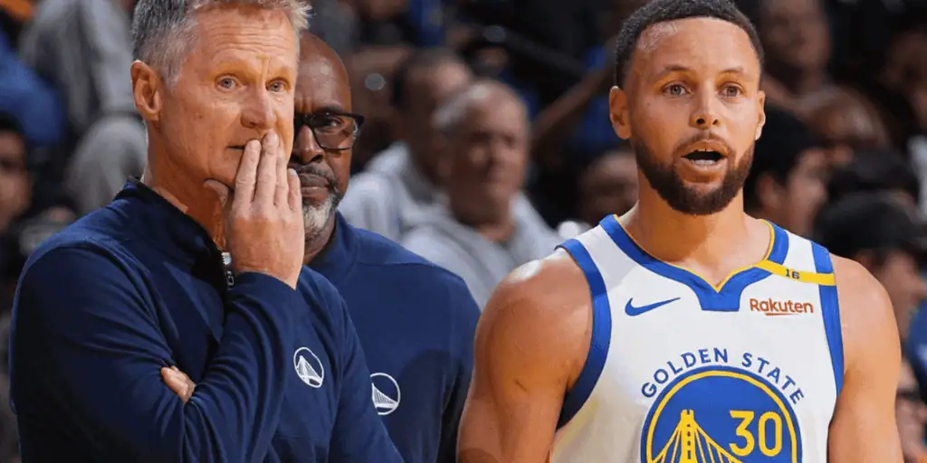 Warriors A basketball coach and player in Golden State Warriors jerseys stand together in a lively arena, discussing a game strategy.