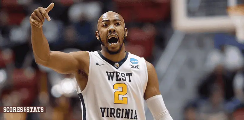 West Virginia Mountaineers vs Arizona Wildcats Picks and Predictions January 7th 2025 2 A West Virginia University basketball player wearing a white jersey with the number 2, passionately directing his teammates during a game.