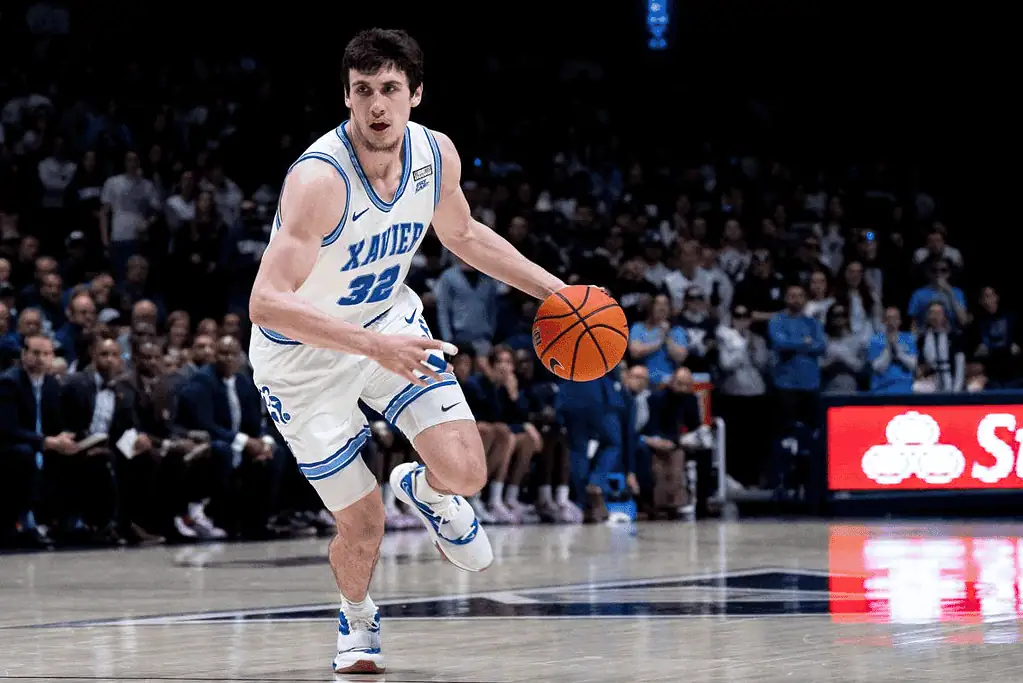 Xavier Musketeers vs Villanova Wildcats Picks and Predictions January 14th 2025 2 A basketball player in a blue jersey dribbles the ball while sprinting across the court, surrounded by an excited crowd.