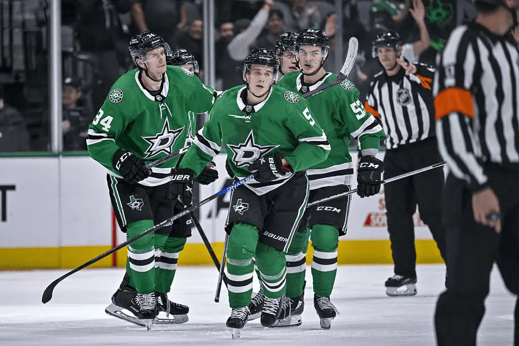 Toronto Maple Leafs vs Dallas Stars Picks and Predictions January 14th 2025 2 Four hockey players in green jerseys celebrate a goal on the ice, with a referee in a striped shirt observing the scene.