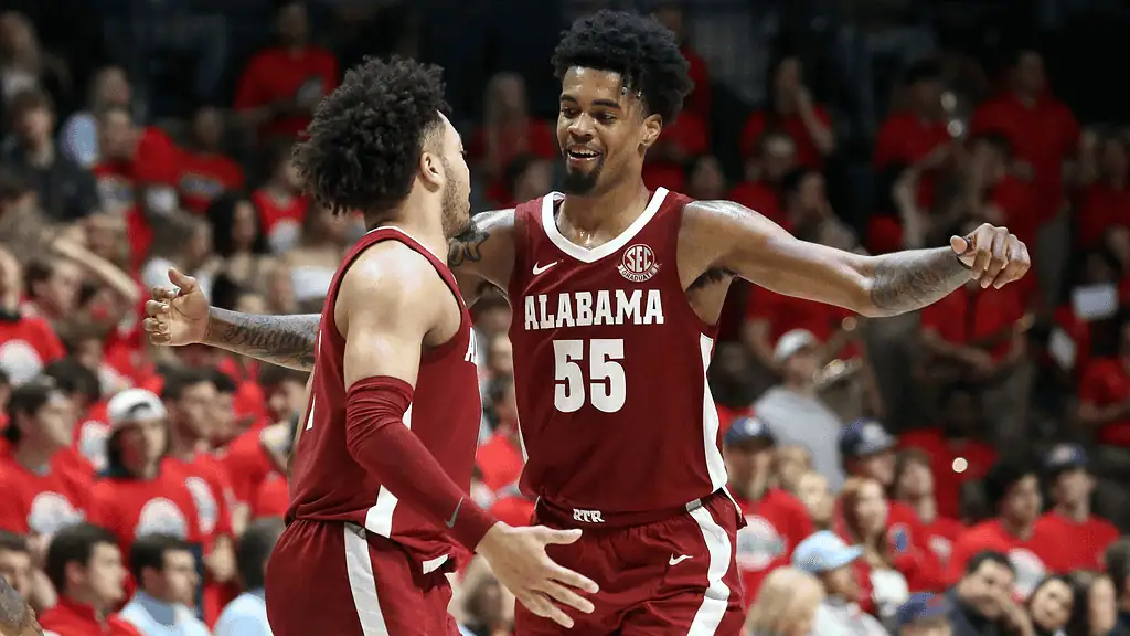 Missouri Tigers vs Alabama Crimson Tide Picks and Predictions February 19th 2025 3 Two Alabama basketball players celebrate in red and white uniforms, surrounded by a cheering crowd in a vibrant arena.