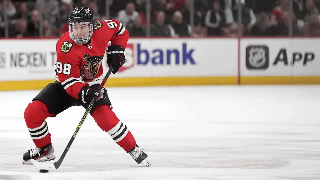 Chicago Blackhawks player wearing jersey number 98 skates intensely with the puck on his stick during an NHL game