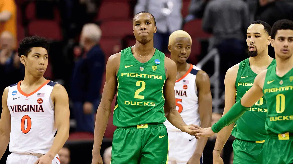 Iowa Hawkeyes vs Oregon Ducks Picks and Predictions February 19th 2025 3 Four college basketball players walk off the court, wearing green and orange jerseys, during a tense moment in a game.