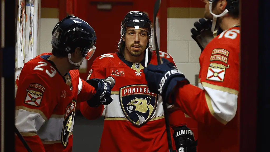 Florida Panthers vs New York Islanders Picks and Predictions February 2nd 2025 2 A trio of hockey players in red Florida Panthers jerseys gather in a hallway, preparing to enter the rink, sticks in hand.