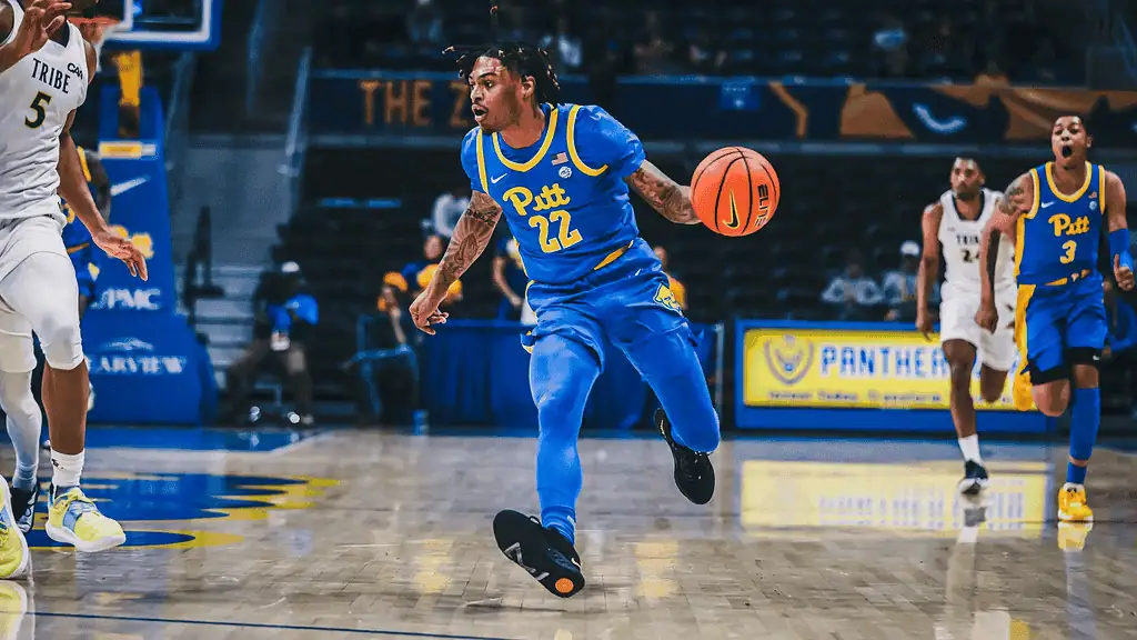 Pittsburgh Panthers vs Georgia Tech Yellow Jackets Picks and Predictions February 25th 2025 3 A basketball player in a blue and yellow uniform dribbles the ball during an intense game against opponents in white uniforms.