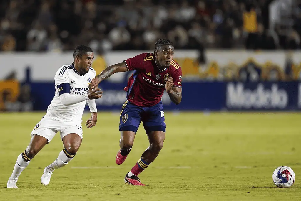 Real Salt Lake vs Seattle Sounders Fc Picks and Predictions March 1st 2025 2 A player in a red jersey races past an opponent in white during an intense soccer match, both focused on the ball.