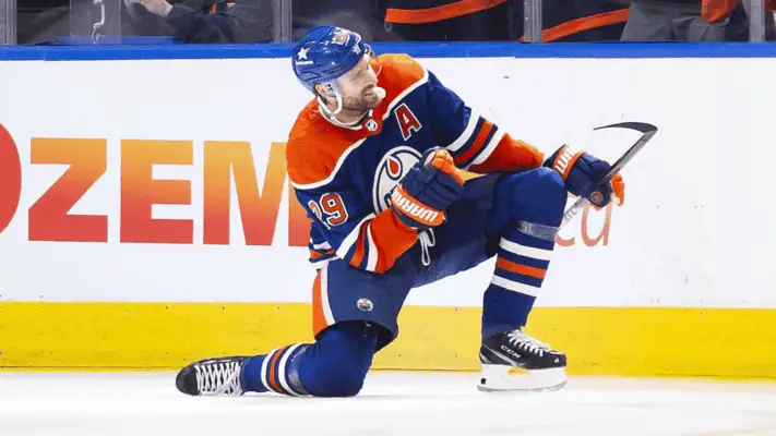  Leon Draisaitl of the Edmonton Oilers kneeling on the ice in celebration after scoring a goal during an NHL game.