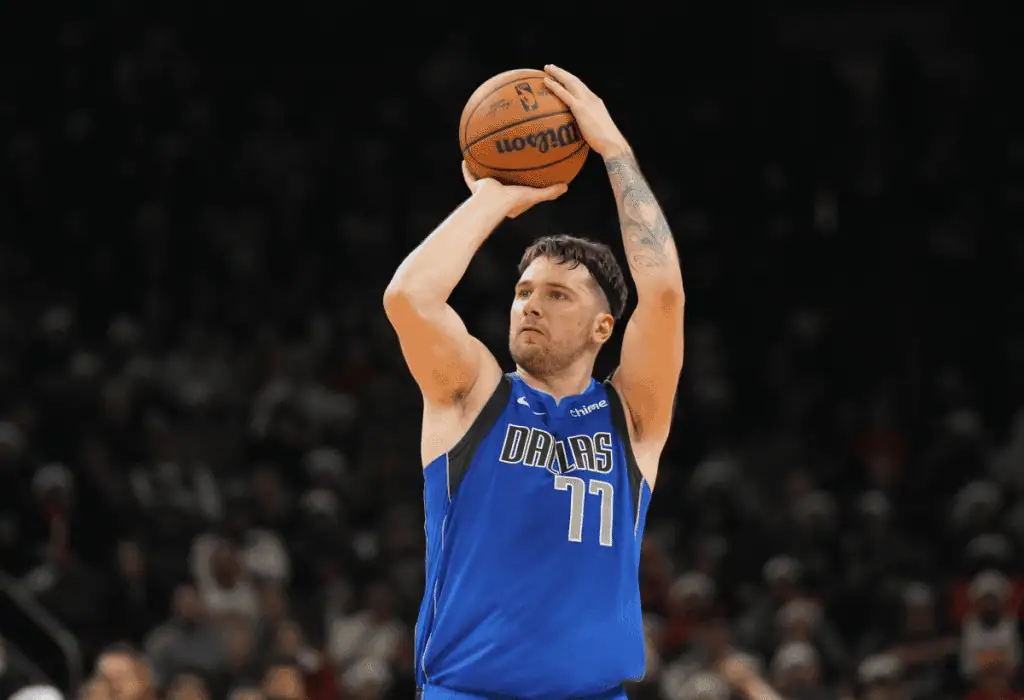Portland Trail Blazers vs Los Angeles Lakers Picks and Predictions February 20th 2025 2 A basketball player in a blue jersey with "DALLAS" is poised to shoot the ball in a packed arena.