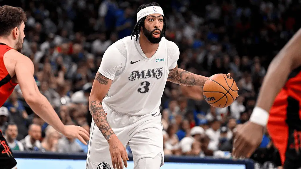 Dallas Mavericks vs Sacramento Kings Picks and Predictions February 10th 2025 2 A basketball player in a white Mavericks jersey dribbles the ball while facing a defender in a black and red jersey during a game.