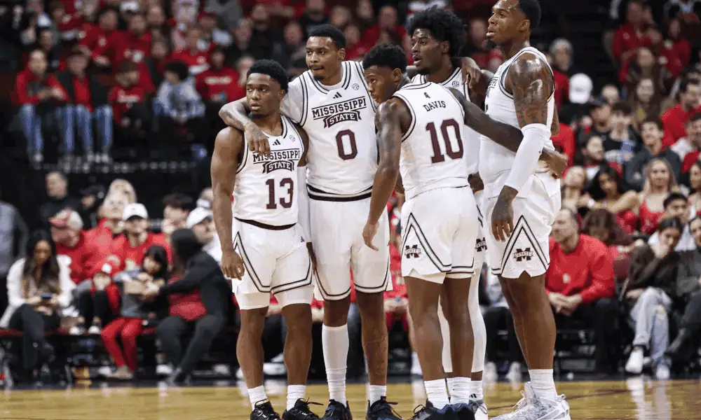 Mississippi State Bulldogs vs Florida Gators Picks and Predictions February 11th 2025 2 A group of Mississippi State basketball players in white uniforms huddles together on the court, with a lively audience in the background.