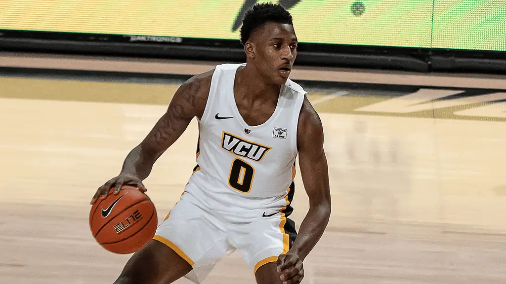 Florida State Seminoles vs Notre Dame Fighting Irish Picks and Predictions February 4th 2025 3 A basketball player in a VCU uniform dribbles a ball during a game, showcasing agility and focus on the court.