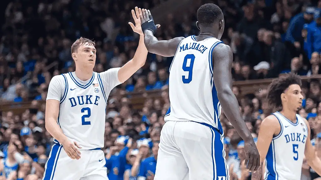 Duke Blue Devils vs Wake Forest Demon Deacons Picks and Predictions March 3rd 2025 2 Two Duke basketball players celebrate with a high-five on the court, surrounded by cheering fans in the background.