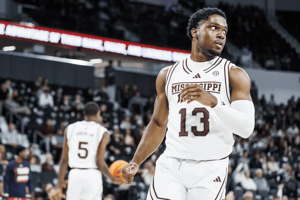 Mississippi State Bulldogs vs Texas Longhorns Picks and Predictions March 4th 2025 2 A Mississippi State basketball player in a white jersey with the number 13 prepares to pass the ball, with spectators in the background.