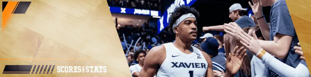 Xavier Musketeers vs Creighton Bluejays Picks and Predictions March 1st 2025 3 A basketball player from Xavier University celebrates with fans on the court, surrounded by an energetic crowd during a game.