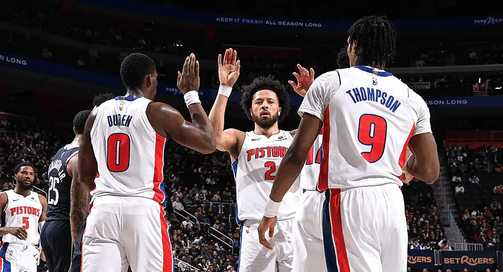 Detroit Pistons players celebrate and high-five each other on the court during a game, showcasing teamwork and excitement.