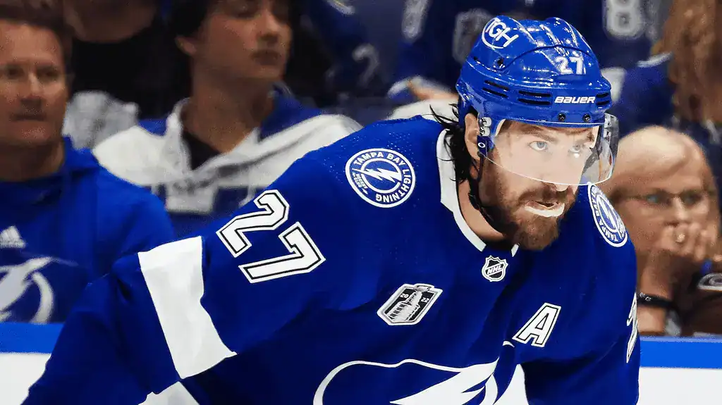 Florida Panthers vs Tampa Bay Lightning Picks and Predictions March 3rd 2025 4 A hockey player in a blue Tampa Bay Lightning jersey focuses on the game, surrounded by enthusiastic fans in the stands.